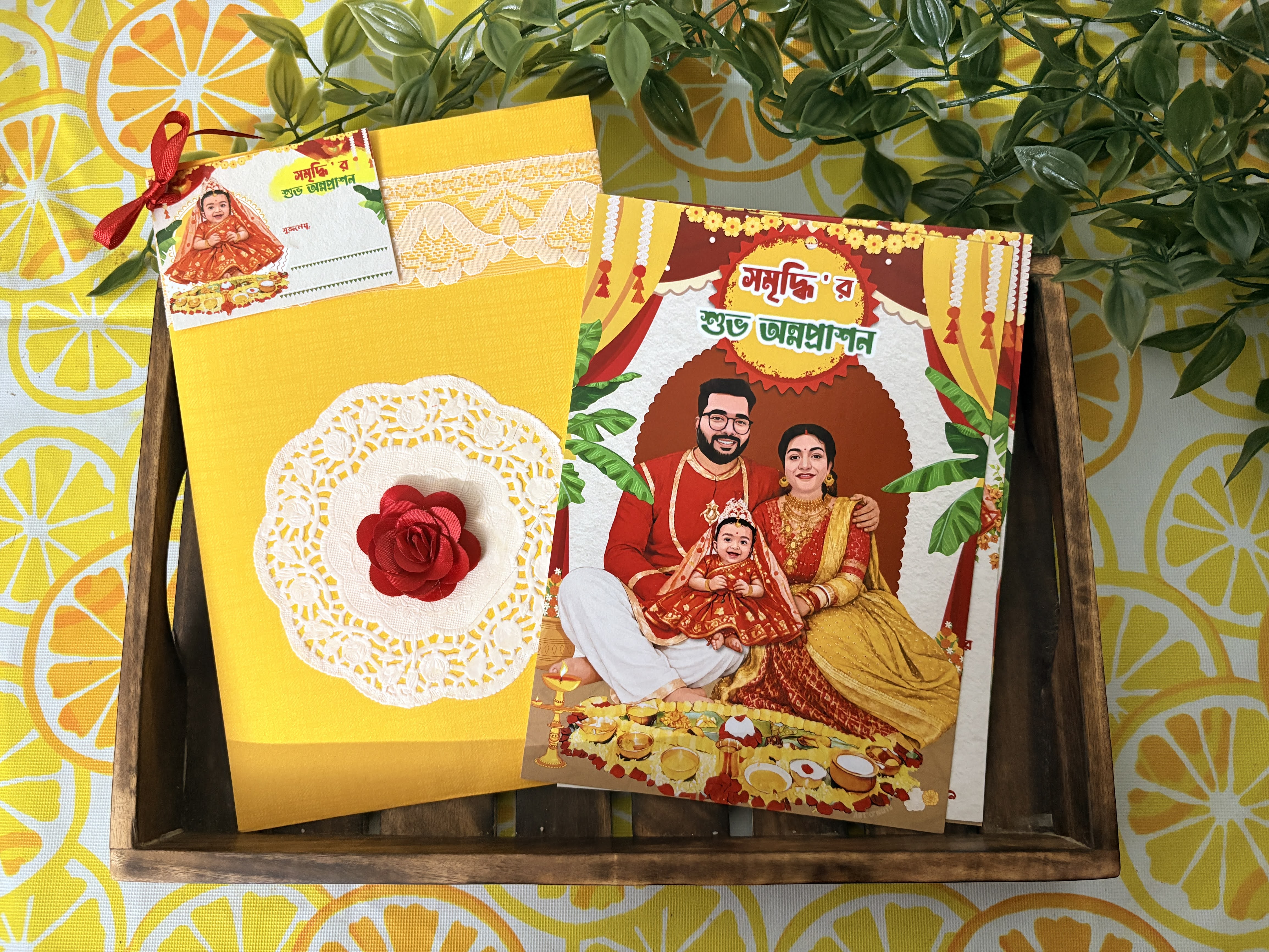 Physical invitation: yellow envelope with lace, rose and illustrated card in wooden tray